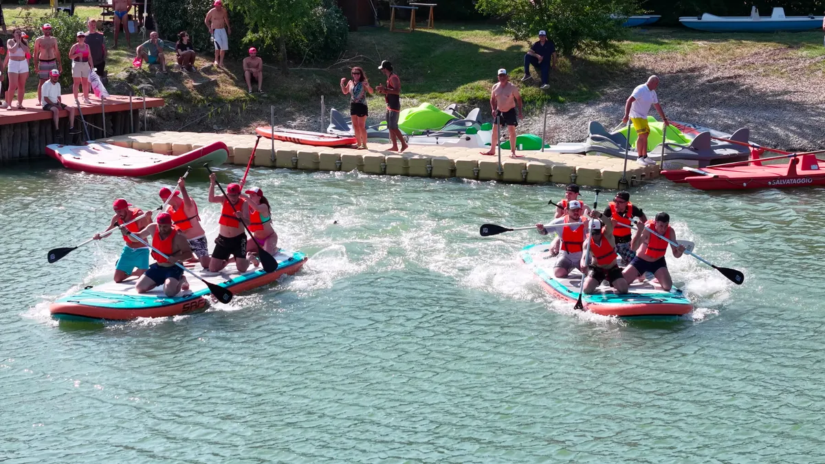 Due squadre di colleghi in regata su SUP giganti durante un team building aziendale