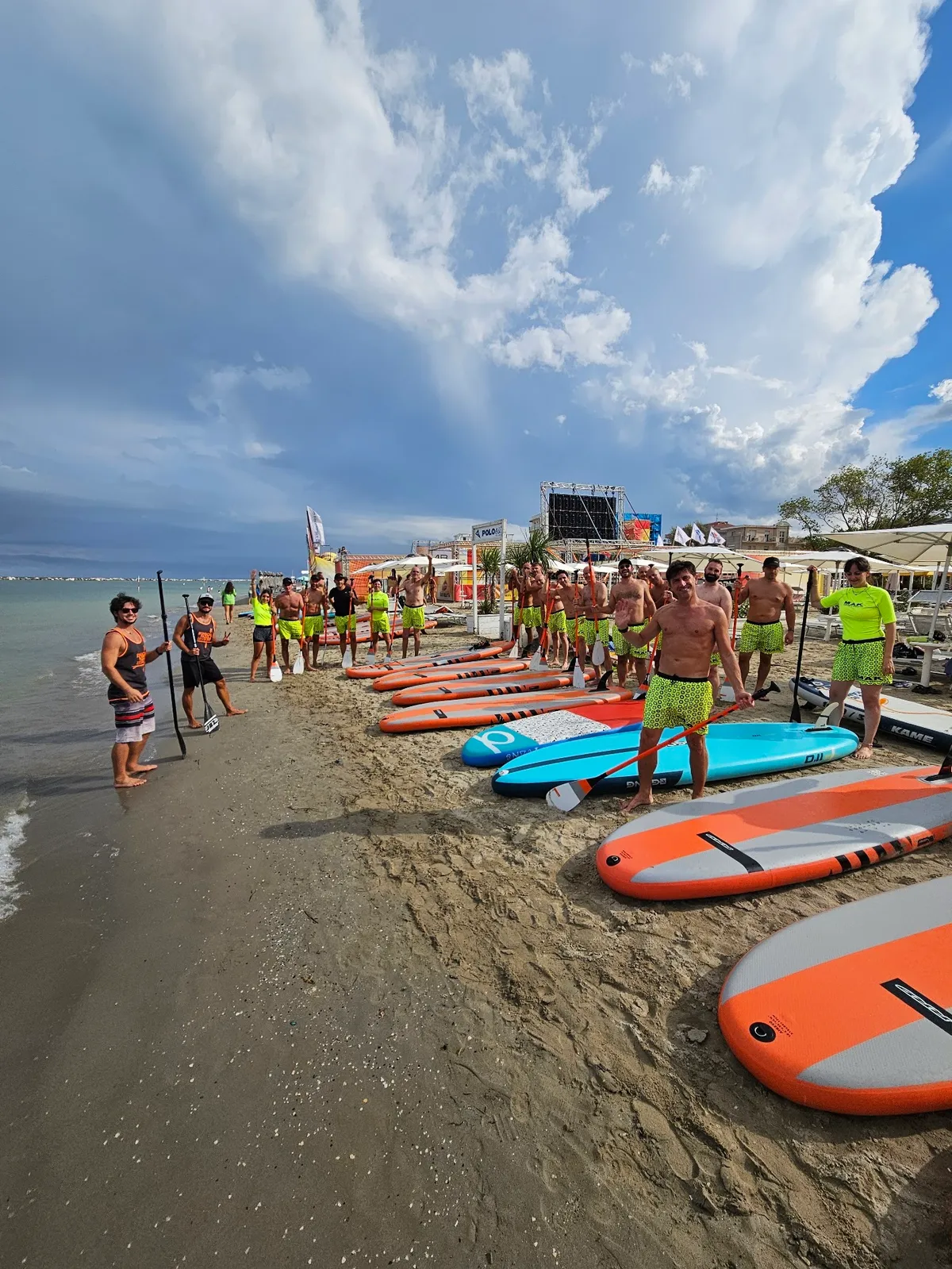 Gruppo aziendale in spiaggia con le tavole da SUP pronte per la sfida